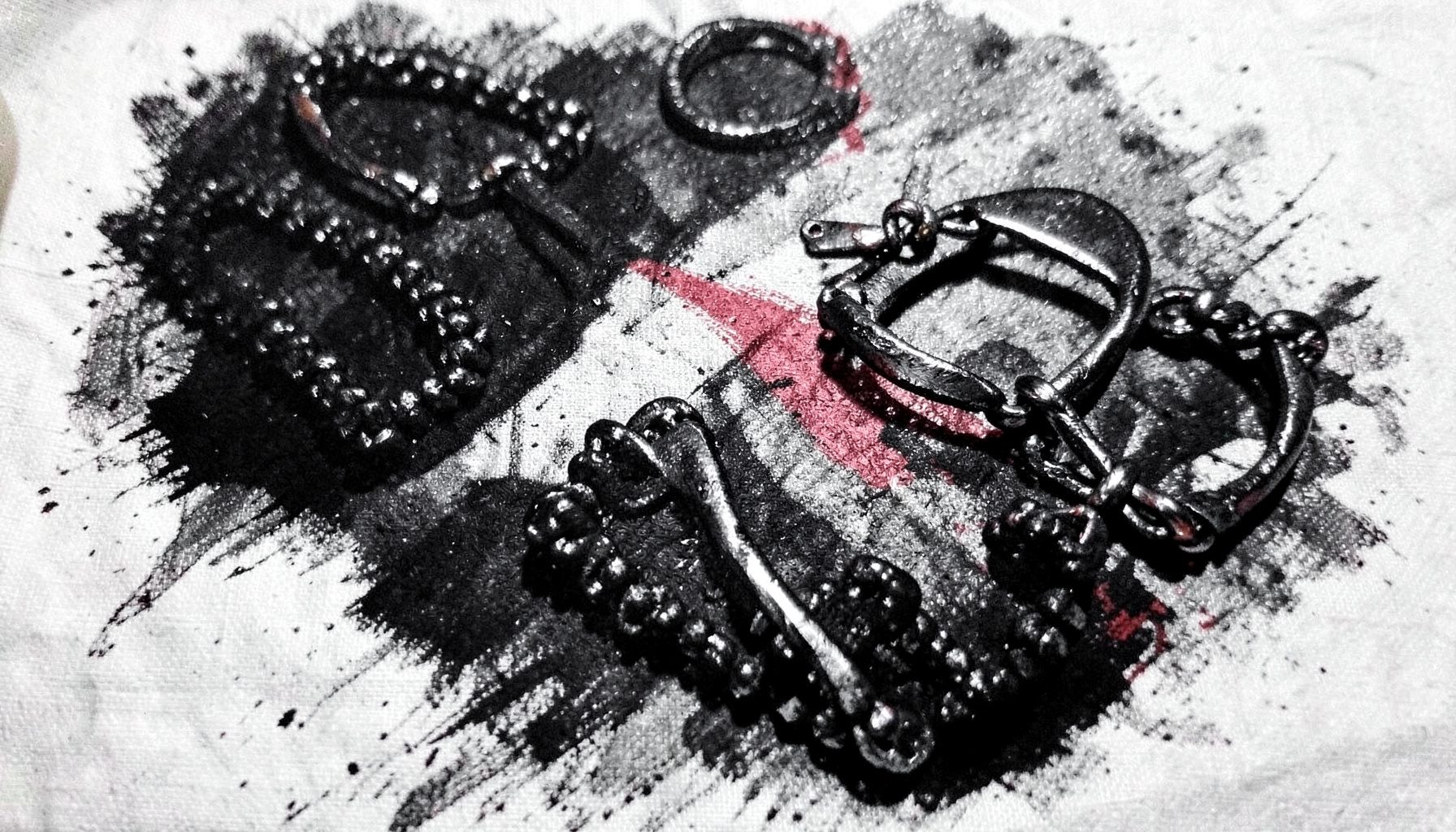 Bold charcoal drawing of handcrafted jewelry laid out on linen, dramatic shadows, dark blacks with a glint of metallic light.
